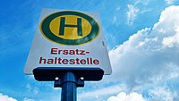 Haltestellenschild mit grünem H in gelbem Kreis. Darunter in roter Schrift "Ersatzhaltestelle". 