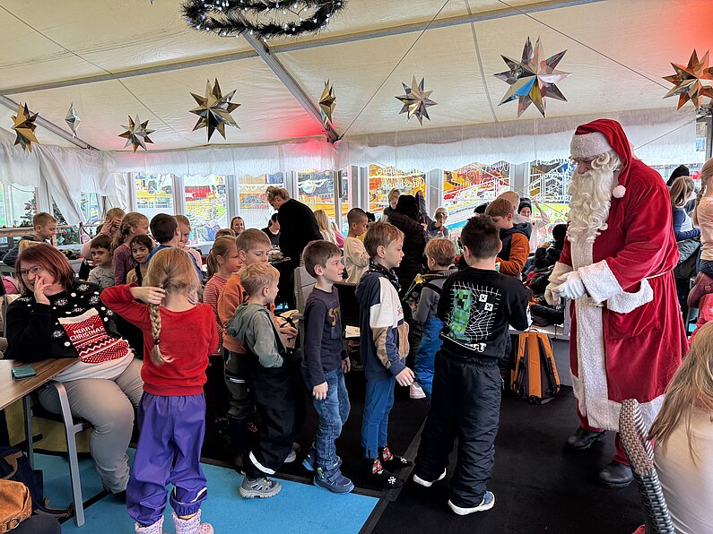 Im neu.sw Bistro bilden Kinder eine Schlange vor dem Weihnachtsmann, der Geschenke verteilt.