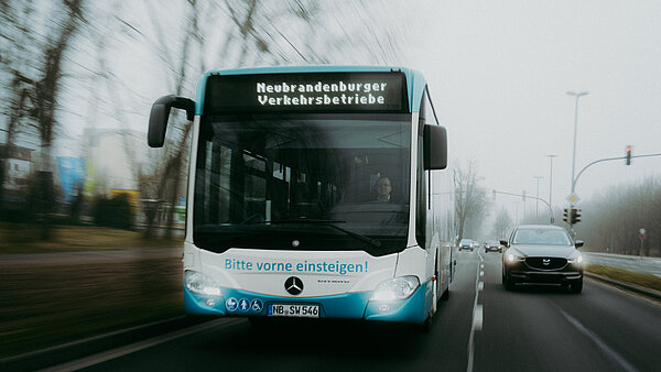 Frontalansicht eines Neubrandenburger Stadtbusses, der auf einer Straße fährt.