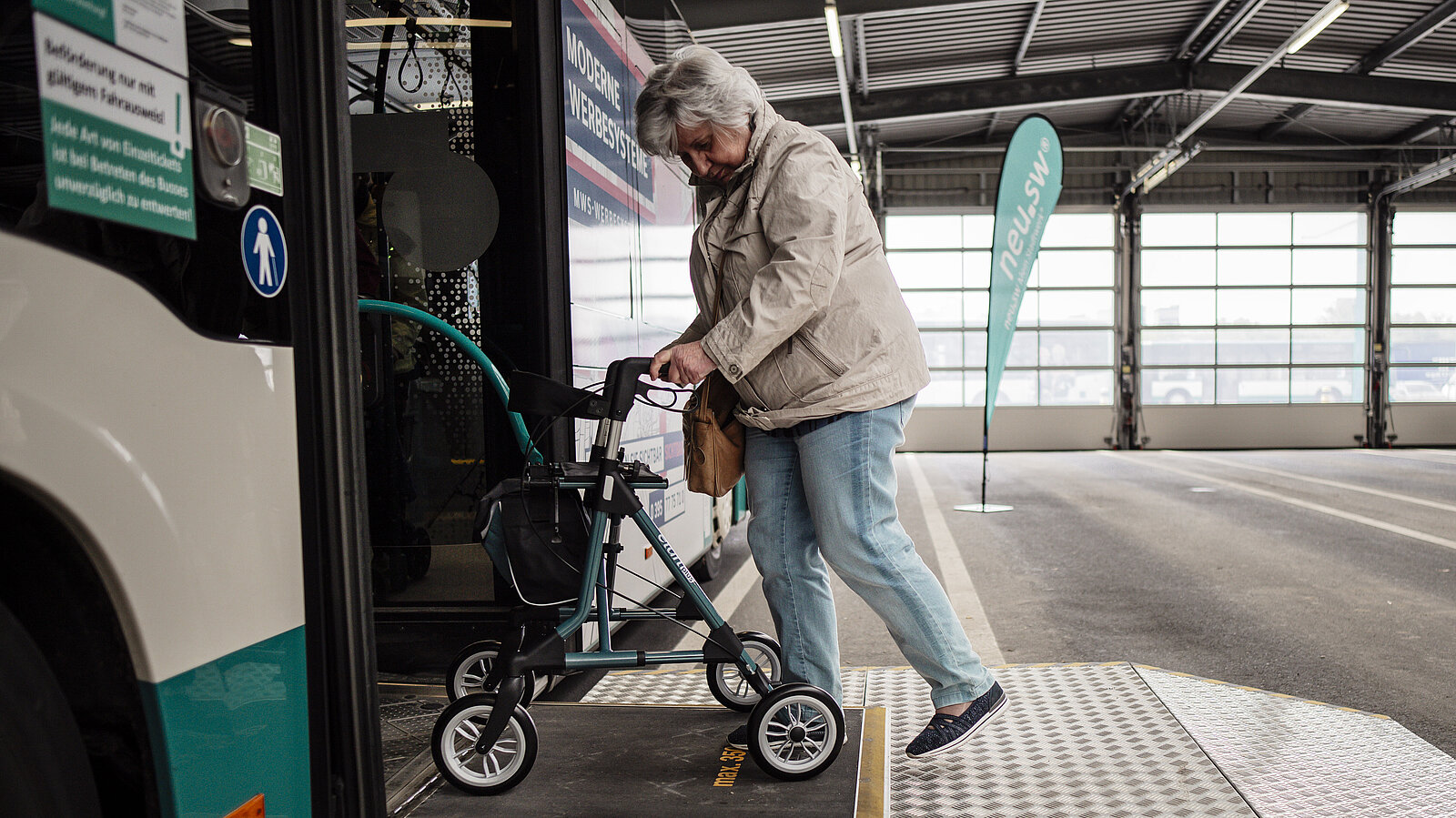 Eine Dame mit Rollator steigt rückwärts aus dem Bus aus