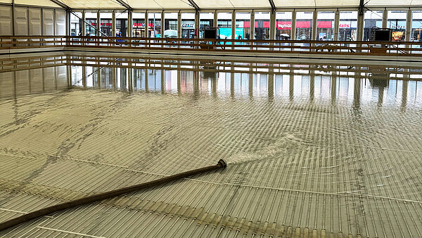 WAsser fließt aus Wasserschlauch, der auf auf schmalen weißen Röhrchen liegt. 