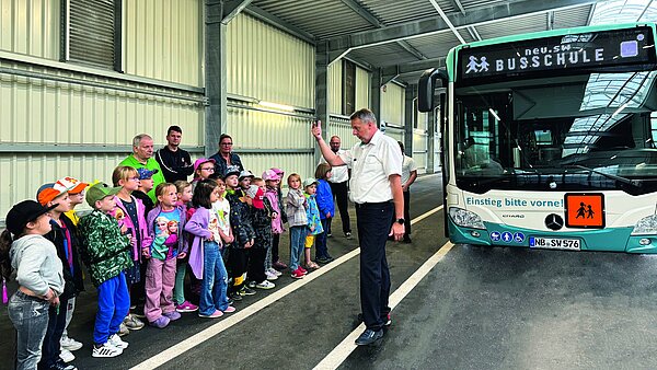 Kinder stehen vor dem Bus und erhalten eine Erklärung vom Busfahrer