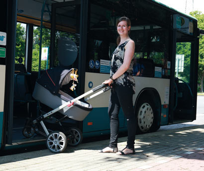 Frau mit Kinderwagen steigt zu ihrer Sicherheit rückwärts aus dem Bus